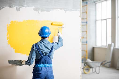 painter painting wall with yellow paint